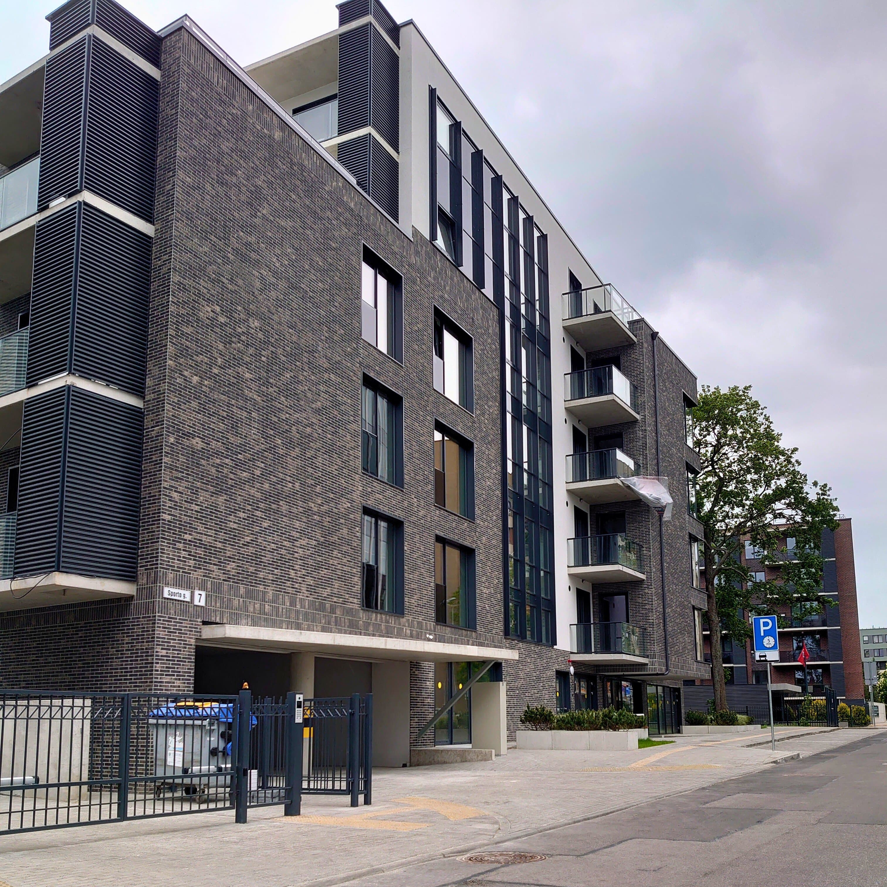 Didelis pastatas su jau įrengtais langais ir erdvia automobilių stovėjimo aikštele.