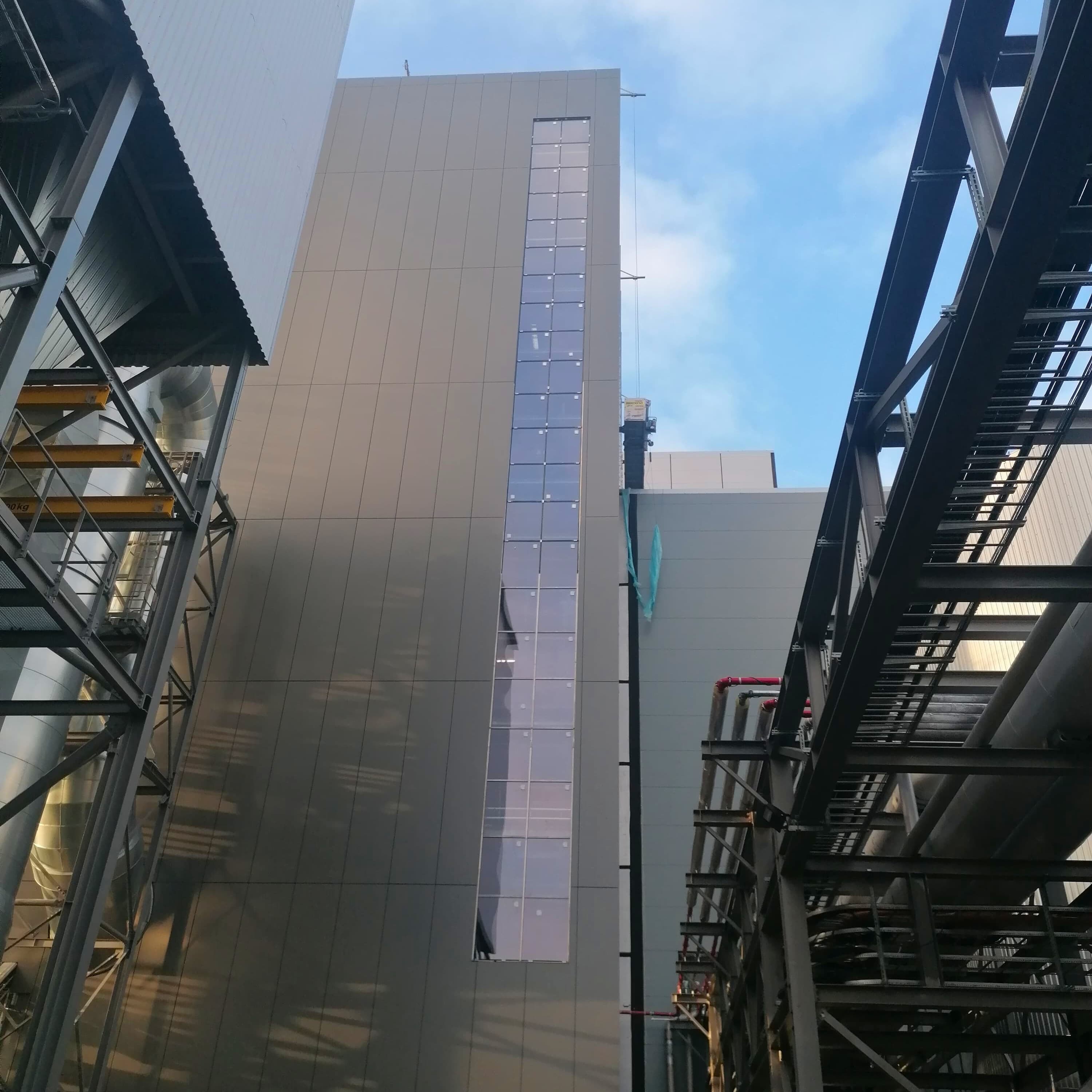 Pastatas Lietuvoje su didžiule metaline siena ir kopėčiomis, žymintis fasado montavimo darbų pabaigą.