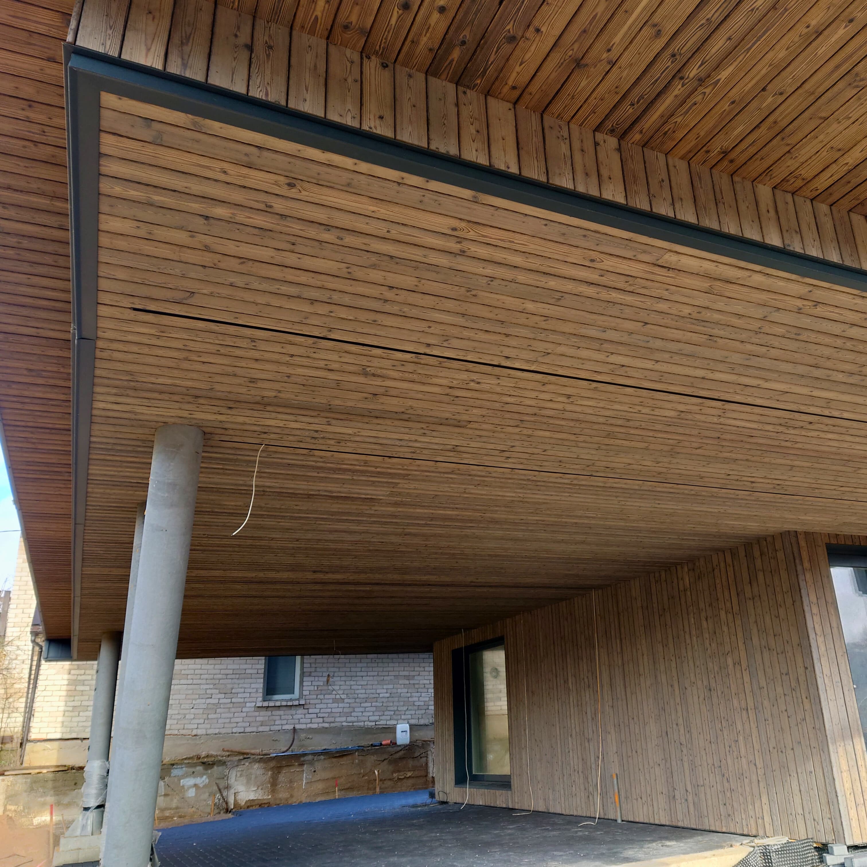 Medinio namo interjeras su medinėmis lubomis ir grindimis, papildytas kaimišku mediniu fasadu.